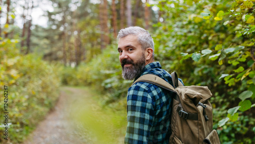 Handsome man standing in the middle of nature, enjoying peaceful atmosphere of the forest, forestbathing.