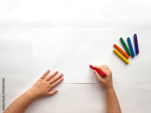 Child drawing with vibrant crayons on white paper