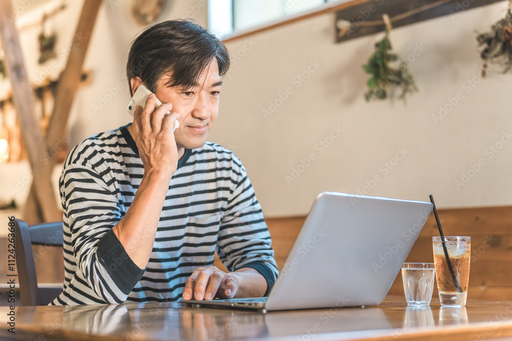 コワーキングスペースでスマホで通話中のテレワーク・リモートワークする男性
コワーキングスペースでスマホで通話中のテレワーク・リモートワークする男性