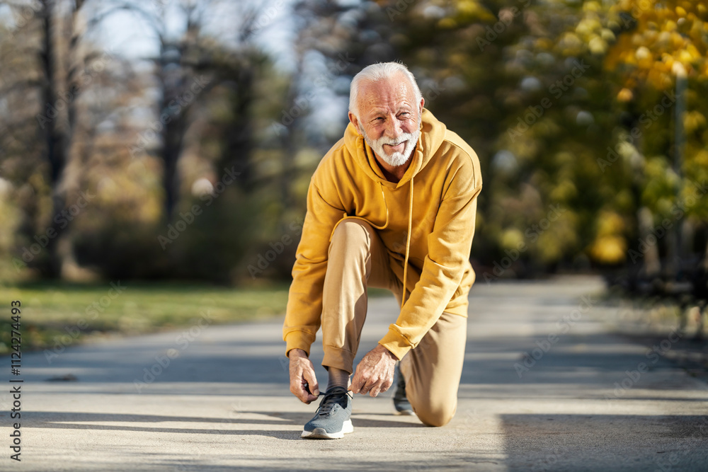 A senior man in sportswear is kneeling in park and preparing for outdoor fitness. A senior man in sportswear is kneeling in park and preparing for outdoor fitness.
