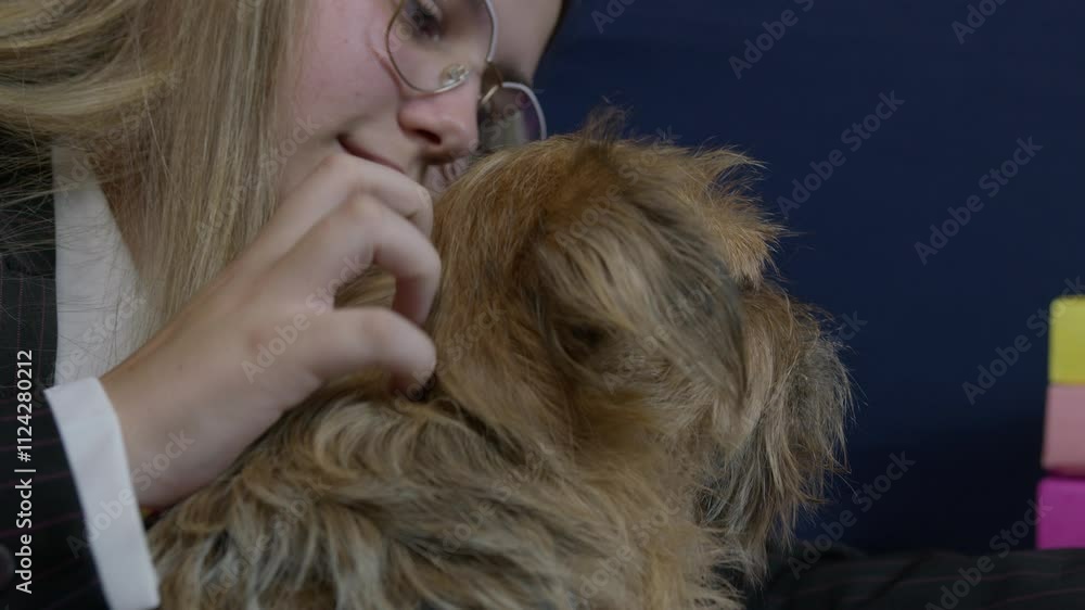 A young caucasian woman in a business suit holding dog while working on her laptop. Close up revealing shot A young caucasian woman in a business suit holding dog while working on her laptop. Close up revealing shot