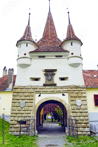 Fairytale Europe: view of the Catherine's Gate built in Brasov by the tailors' guild. Medieval architecture in Transylvania: beautiful city gate with corner turrets and the coat of arms of Brașov photo