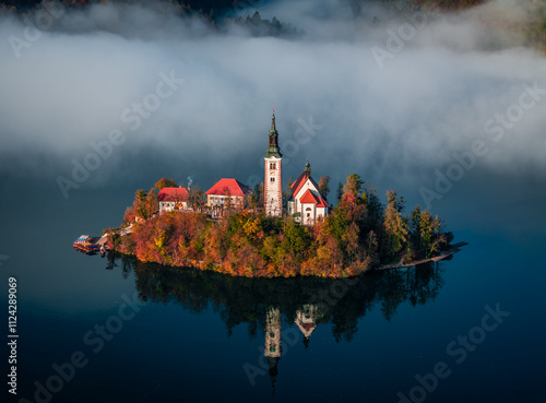 Obraz na płótnie Bled, Slovenia - Beautiful foggy autumn sunrise at Lake Bled with the famous Pilgrimage Church of the Assumption of Maria (Bled Island) with heavy fog behind on an October morning w salonie