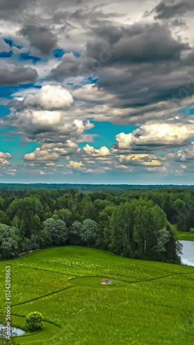 Fluffy white clouds drift across a vivid blue sky above a lush green horizon in a serene view photo