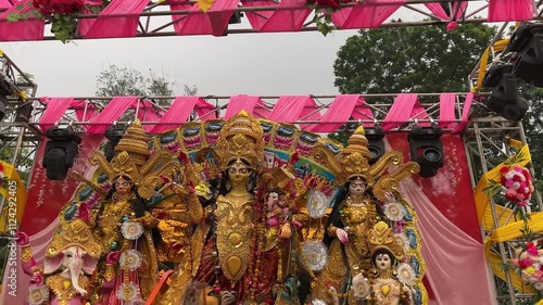 The Maa Durga idol stands majestically on an open stage, flanked by Laxmi, Saraswati, Ganesh, and Kartick. photo