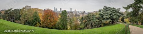 Paris, France - 11 16 2024: Park Buttes Chaumont. Panoramic view of remarkable trees and vegetation with fall colors.