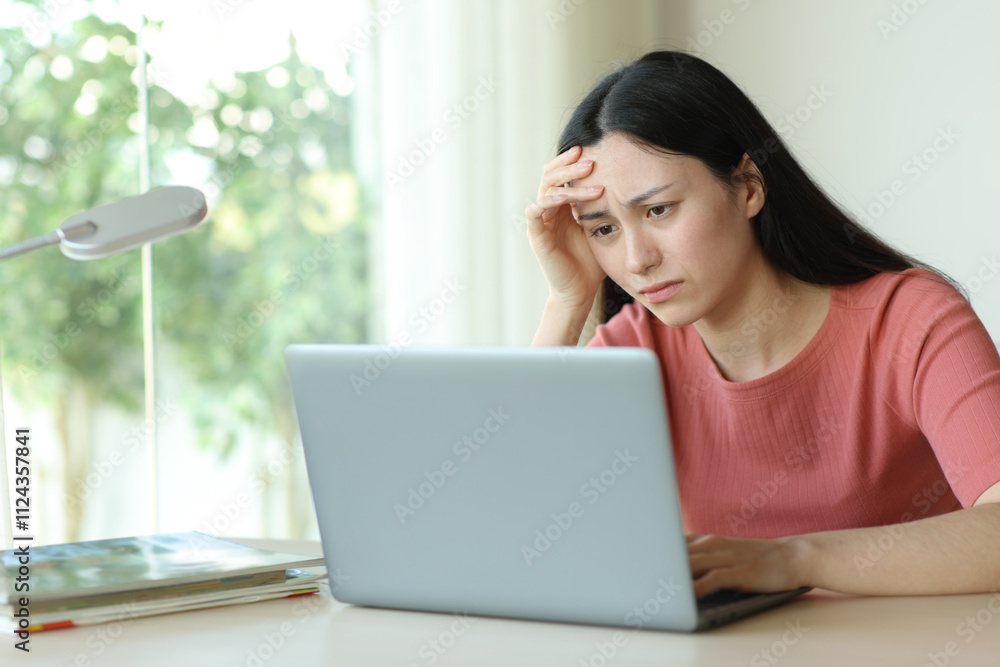 Worried asian woman checking laptop in a room Worried asian woman checking laptop in a room