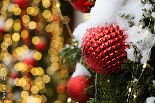 New Year celebration in winter city, Christmas tree branches with red balls covered with snow on golden lights background photo