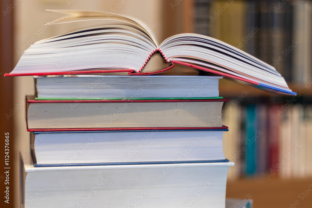 An open book lies on a stack of hardcover books An open book lies on a stack of hardcover books
