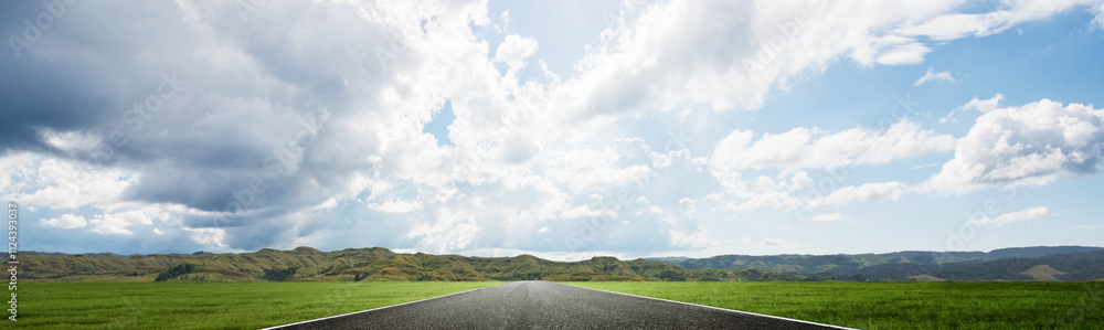 Asphalt street with mountain range with blue sky and clouds in the background Asphalt street with mountain range with blue sky and clouds in the background