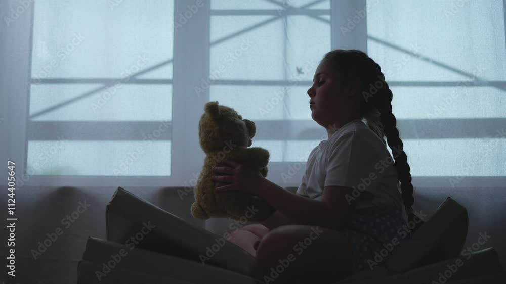 Child clings to teddy bear in fear seeking comfort. Silhouette of scared child. Fearful child finds solace holding teddy bear. Child and teddy bear comfort in fearful moments. Teddy bear soothes fear. Child clings to teddy bear in fear seeking comfort. Silhouette of scared child. Fearful child finds solace holding teddy bear. Child and teddy bear comfort in fearful moments. Teddy bear soothes fear.