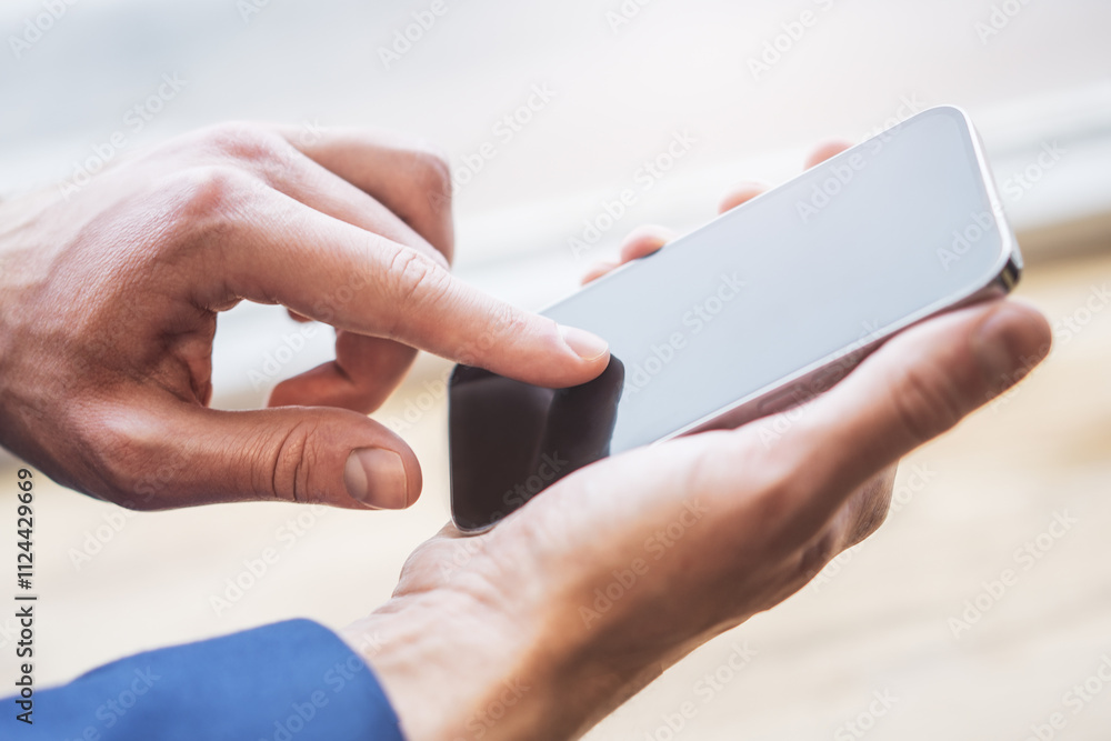 Closeup view of a man engrossed in his smartphone tasks the blurred bustle of an office scene Closeup view of a man engrossed in his smartphone tasks the blurred bustle of an office scene
