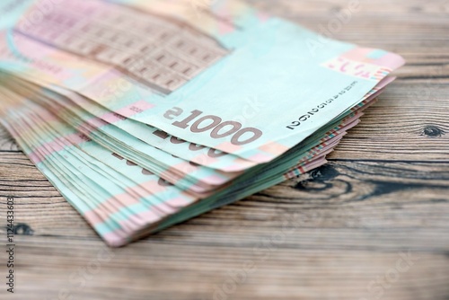 Big amount of ukrainian new one hundred hryvnia money bills with modern design on wooden background. Financial concept, business photo