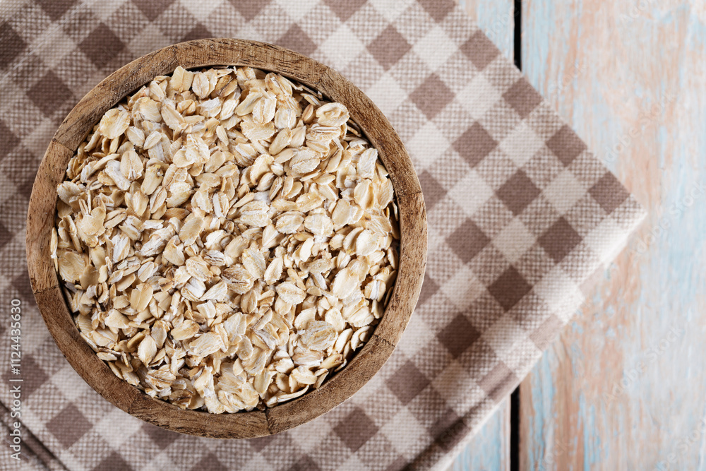 Wooden Bowl with Dry Oatmeal on Checkered Linen Napkin, Top View Wooden Bowl with Dry Oatmeal on Checkered Linen Napkin, Top View