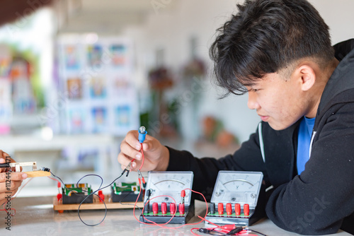 Obraz na plátně Children are studying electrical circuit systems by experimenting with electrical connections using a small electric meter and a small flashlight bulb in physics science class, soft focus