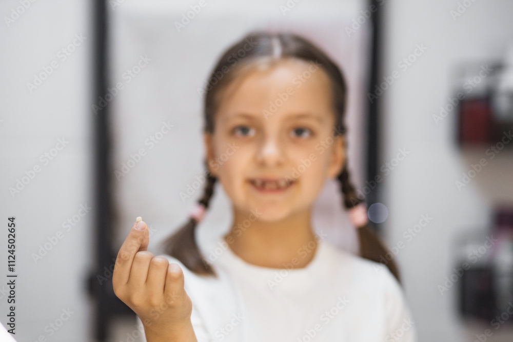 Portrait of young Caucasian girl showing freshly fallen baby tooth while looking into mirror in bathroom, expressing pride and excitement. Portrait of young Caucasian girl showing freshly fallen baby tooth while looking into mirror in bathroom, expressing pride and excitement.