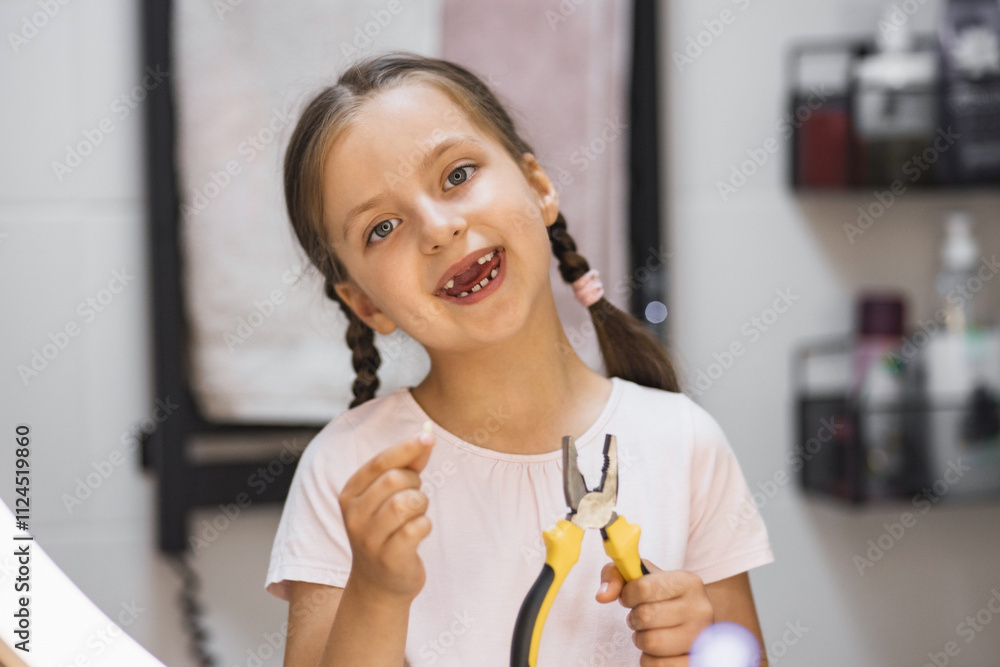 Caucasian girl smiling in bathroom holding fallen baby tooth and pliers, reflecting excitement and achievement after tooth loss. Caucasian girl smiling in bathroom holding fallen baby tooth and pliers, reflecting excitement and achievement after tooth loss.