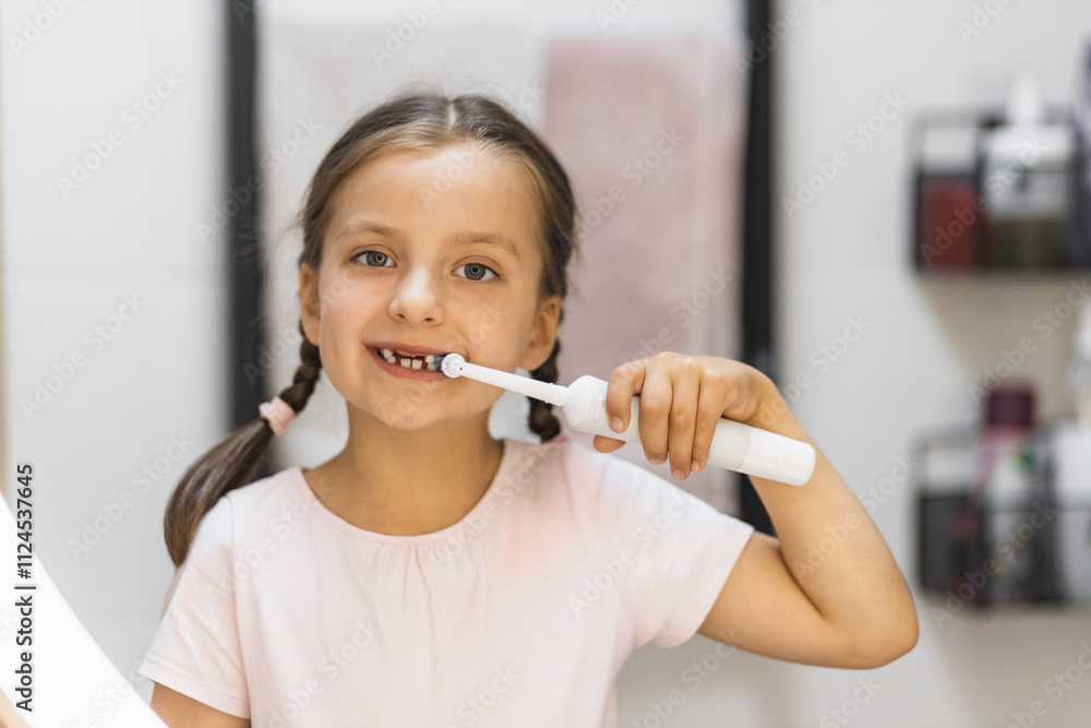 Little Caucasian girl with missing front teeth brushing teeth with electric toothbrush, smiling in bathroom mirror, building healthy habits. Little Caucasian girl with missing front teeth brushing teeth with electric toothbrush, smiling in bathroom mirror, building healthy habits.