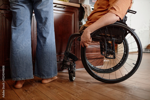 Cropped shot of unrecognizable wheelchaired boy helping mother with breakfast at home photo