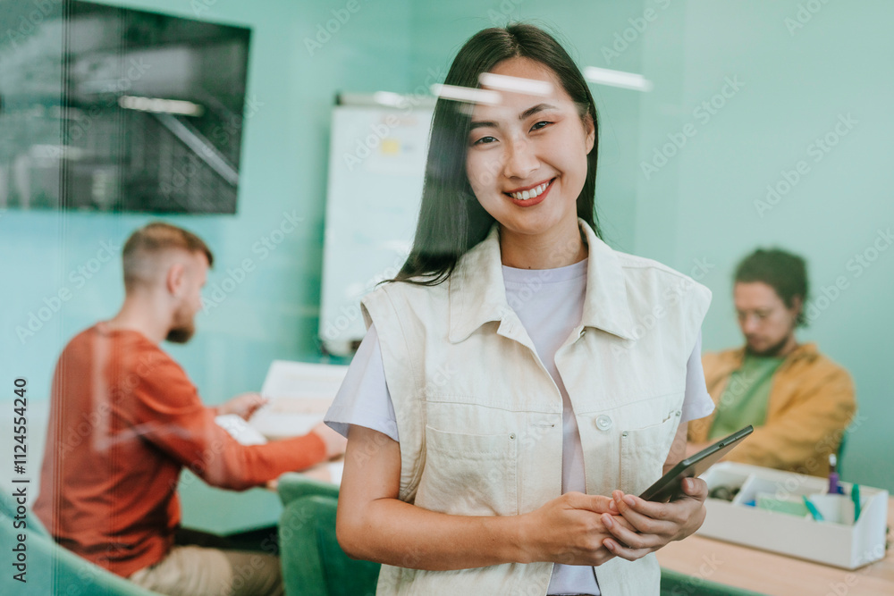 Happy businesswoman standing with tablet PC in front of colleagues at office Happy businesswoman standing with tablet PC in front of colleagues at office