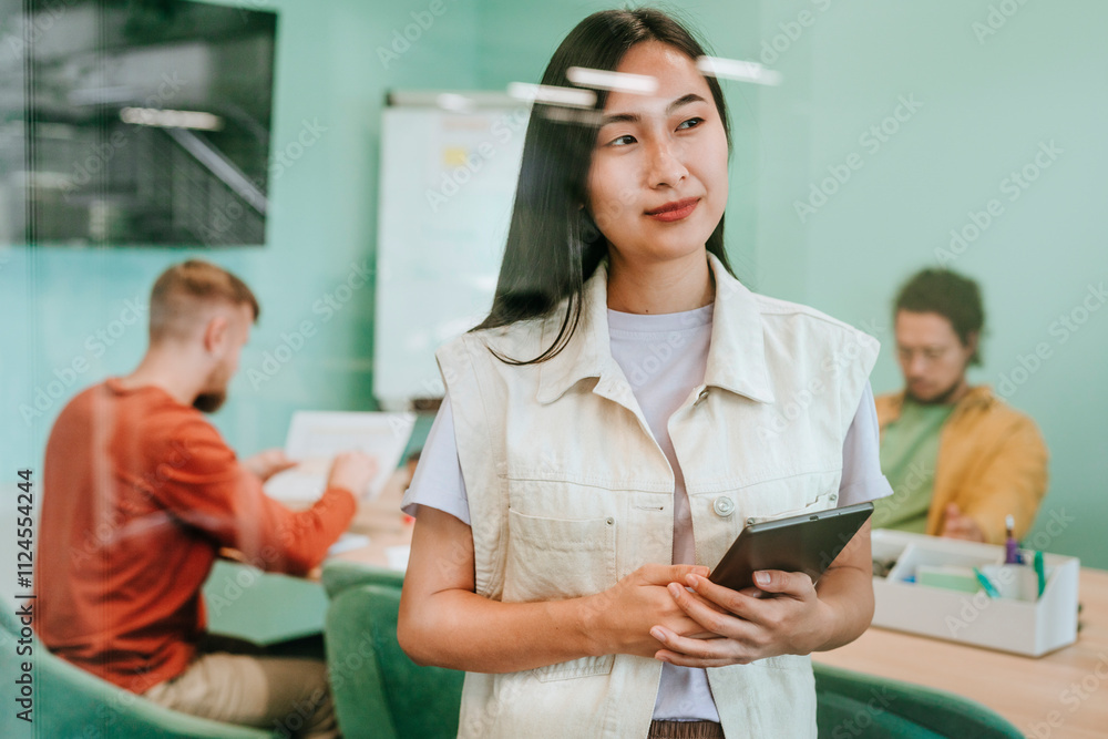 Smiling young businesswoman standing with tablet PC in office Smiling young businesswoman standing with tablet PC in office