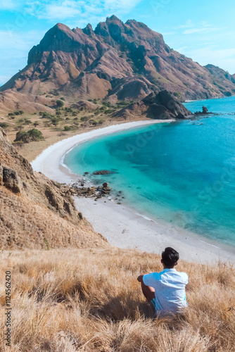 Man hiker watching beautiful ocean coastline and mountain at Padar island in Komodo National Park, Indonesia. summer background and summer holiday concept. photo