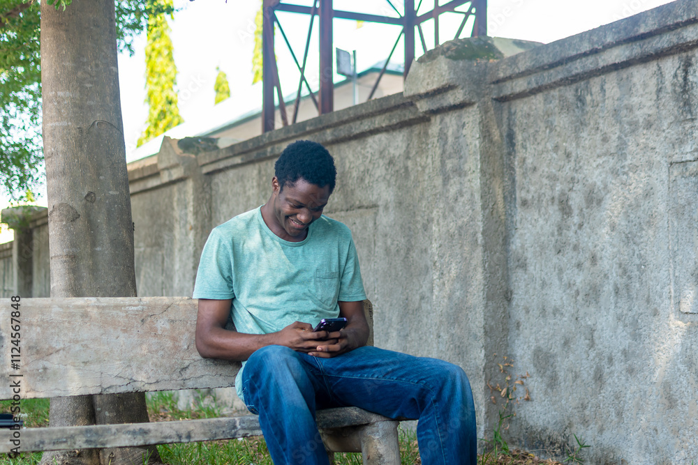 African American man siting in a garden using phone. African American man siting in a garden using phone.