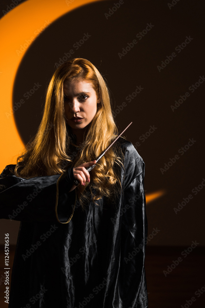 A red-haired woman magician casts a spell with a magic wand against the backdrop of a crescent moon. Portrait of a young sorceress. The concept of magic and sorcery A red-haired woman magician casts a spell with a magic wand against the backdrop of a crescent moon. Portrait of a young sorceress. The concept of magic and sorcery