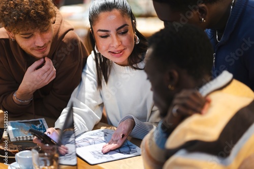 A group of people in a cafe gathered around a table with sketchpads, coffee cups, and pastries, engaged in a collaborative discussion in a bright and inviting environment photo