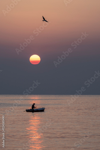 Fisher boat at sunrise in Monopoli, Apulia, Italy with a bird flying overhead photo