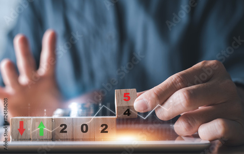 Close-up of a hand adjusting wooden blocks displaying 2025, symbolizing financial trends, predictions, and market analysis for the future.