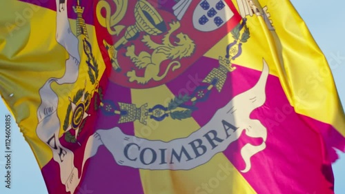 Super close-up of Coimbra's colorful flag gently waving in the breeze beneath a bright blue sky in Portugal