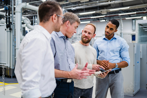 Businessman with digital tablet talking to colleagues in a factory photo