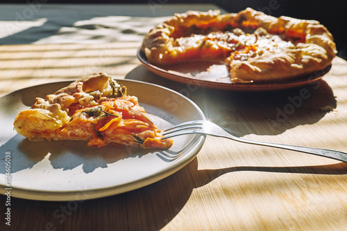 Delicious seasonal tart with baked pumpkin, brie cheese and herbs on wooden table photo