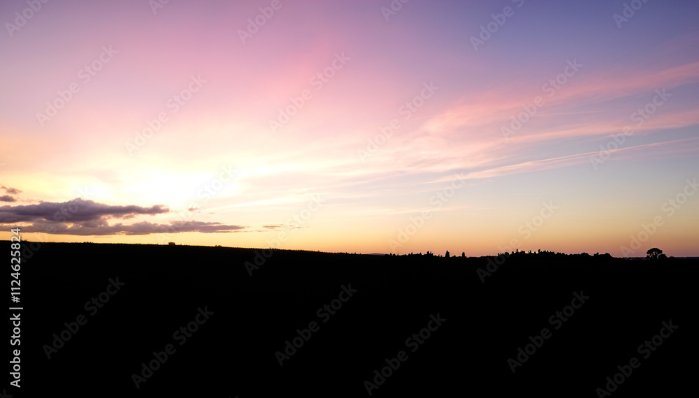Obraz premium Silhouetted landscape with a colorful sunset sky
