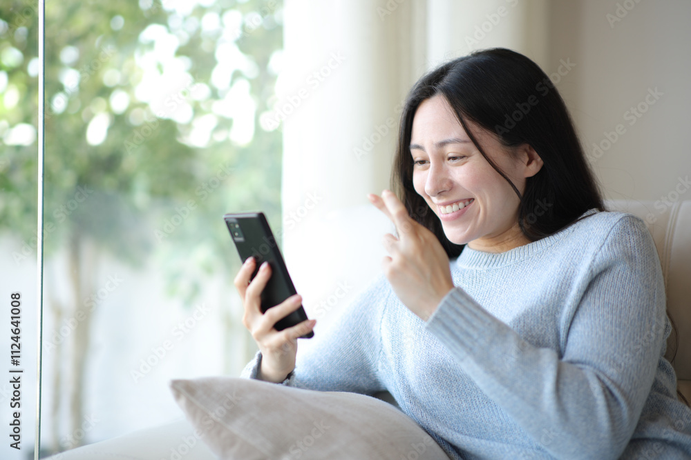 Excited asian woman crossing fingers waiting for result on phone Excited asian woman crossing fingers waiting for result on phone