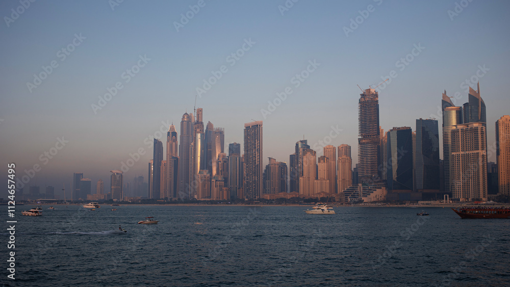 Obraz premium Dubai Marina, view of the shore skyscrapers, evening time, boats are on the water and