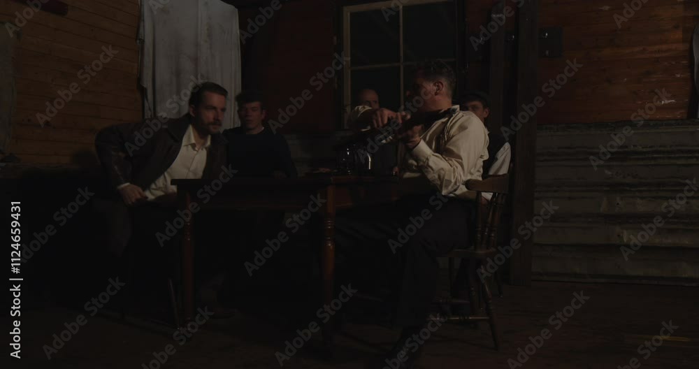 A group of armed men sit around a table in a dark room. They look up, grab their weapons and walk away A group of armed men sit around a table in a dark room. They look up, grab their weapons and walk away