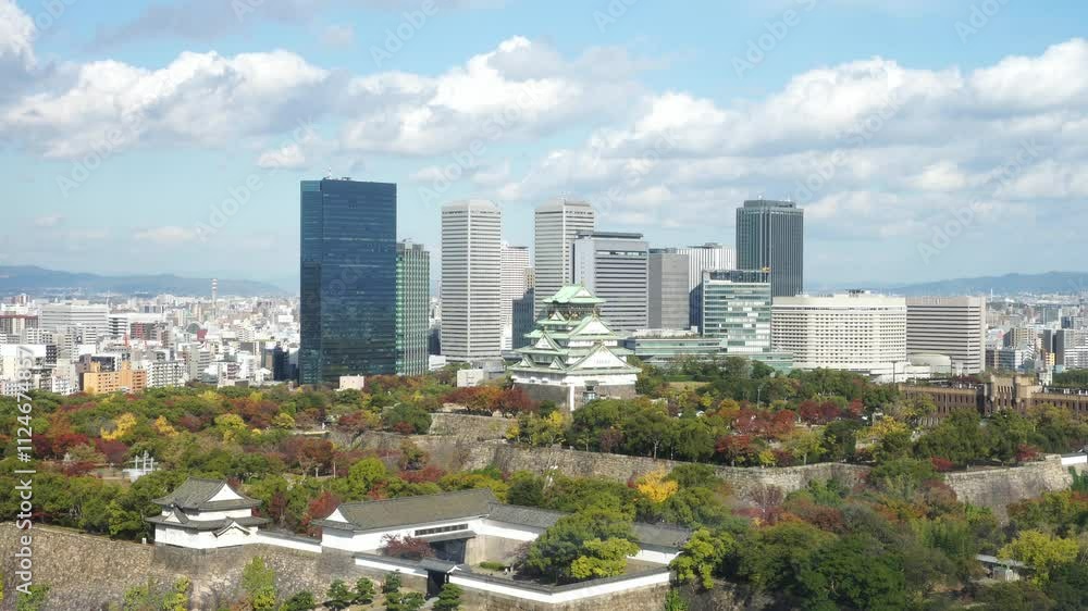 Aerial view of Osaka Castle revealing the Osaka skyline and building city with windward of clouds and blue sky background at Osaka in autumn season (fall foliage). Cityscape, Landmark of Osaka. Aerial view of Osaka Castle revealing the Osaka skyline and building city with windward of clouds and blue sky background at Osaka in autumn season (fall foliage). Cityscape, Landmark of Osaka.