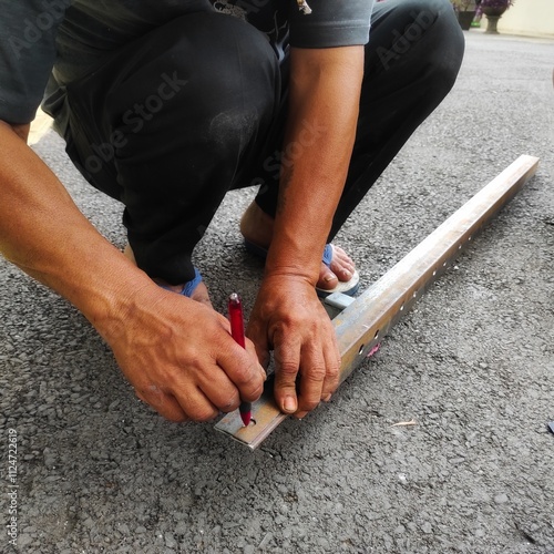 Worker marking a hole on a metal surface with a pen, with a cutting machine or grinder