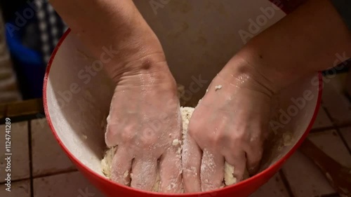 A woman in the kitchen kneading a pizza dough on a wooden board with flour