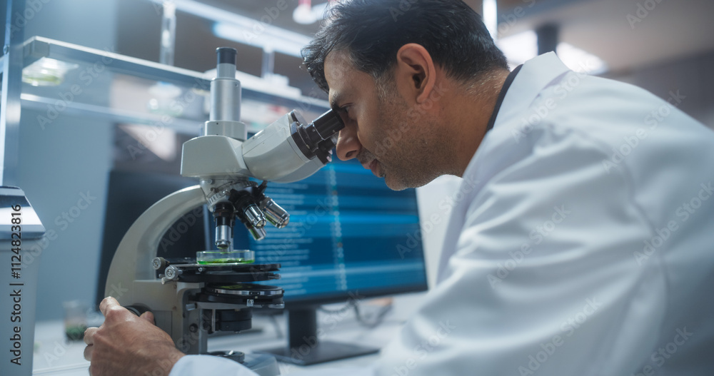 Molecular Biology Research Scientist Looking at a DNA Sample Under a Microscope in an Applied Science Laboratory. Portrait of an Adult Lab Engineer in White Coat Working on Vaccine and Medicine Molecular Biology Research Scientist Looking at a DNA Sample Under a Microscope in an Applied Science Laboratory. Portrait of an Adult Lab Engineer in White Coat Working on Vaccine and Medicine