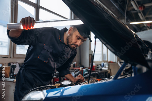 Lighting up the place, under the hood. Mechanic working in a car service station