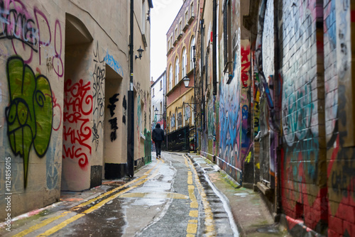 Fototapeta Naklejka Na Ścianę i Meble -  Graffiti Covered Buildings Painted By Street Artists On Small Street In Bristol UK