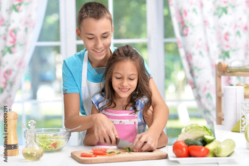Cute little brother and sister preparing salad together at kitchen Cute little brother and sister preparing salad together at kitchen