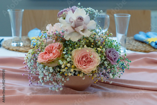 Decorated table of beautiful flowers in vase for wedding or another catered event dinner.