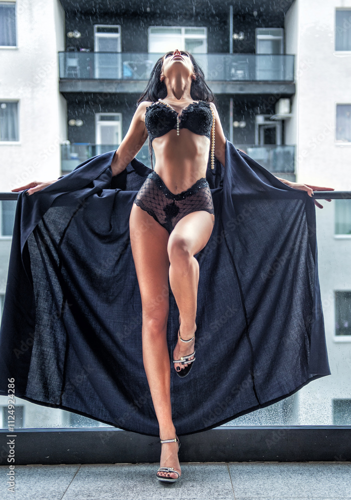 Beautiful brunette woman in black lingerie posing in the city. Elegant and sensual brunette girl with long hair in black lingerie posing on the roof.