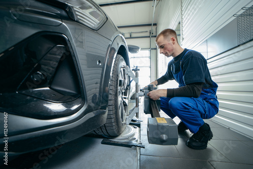 Auto mechanic adjustment automobile wheel alignment work at repair service station photo