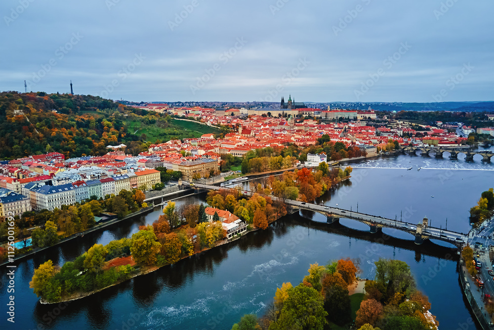 Fototapeta premium Aerial view of cityscape of Prague with colorful autumn trees on island on Vltava river. Architecture of Praha, Czech Republic
