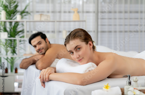 Blissful couple customer having exfoliation treatment in luxury spa salon with warmth candle light ambient. Salt scrub beauty treatment in health spa body scrub. Quiescent